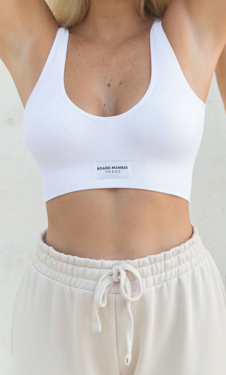 Model wearing THE B.O.D white seamless ribbed bralette and white sweatpants. The Board of Directors Ribbed Bra in White aka Flat White